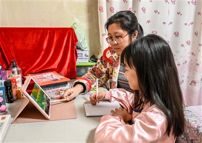 昨日,我市一名小学生在家参加线上学习,家长在一旁指导.